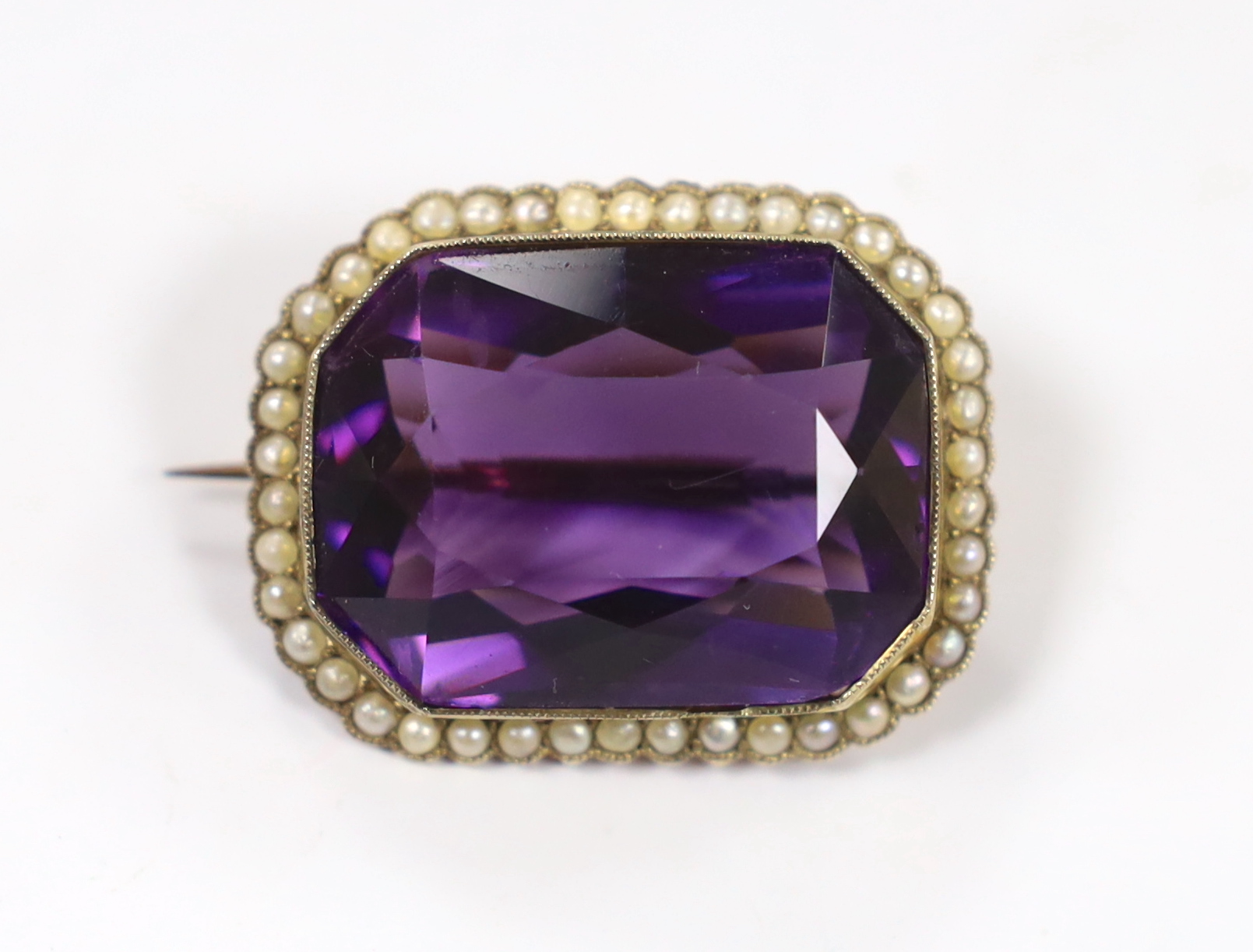 An Edwardian yellow metal mounted emerald cut amethyst and seed pearl cluster set brooch, 31mm, gross weight 11.9 grams.